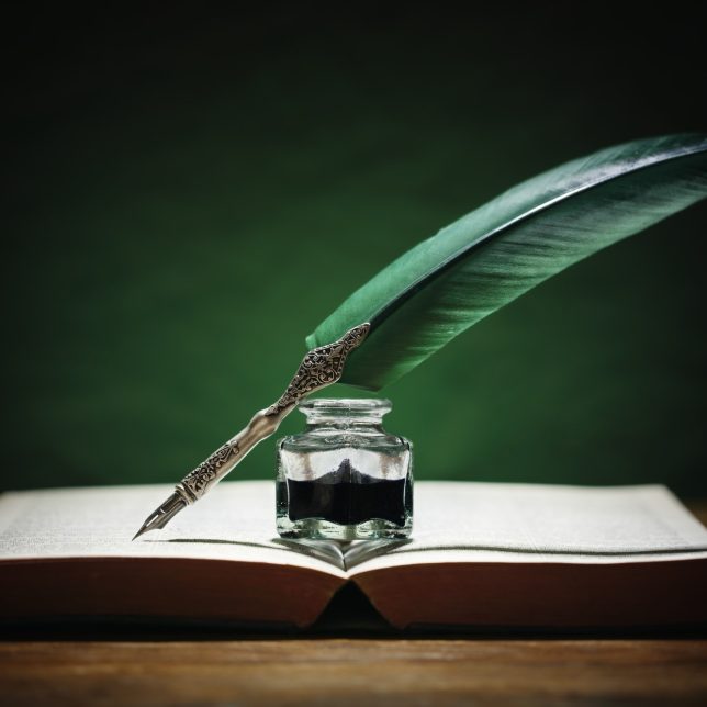 Quill pen and inkwell on old book