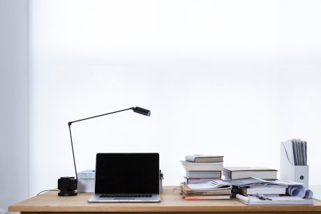 Image of desk with a laptop and some books stacked next to it