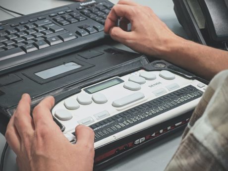 Image of a blind man using a braille screen reader.